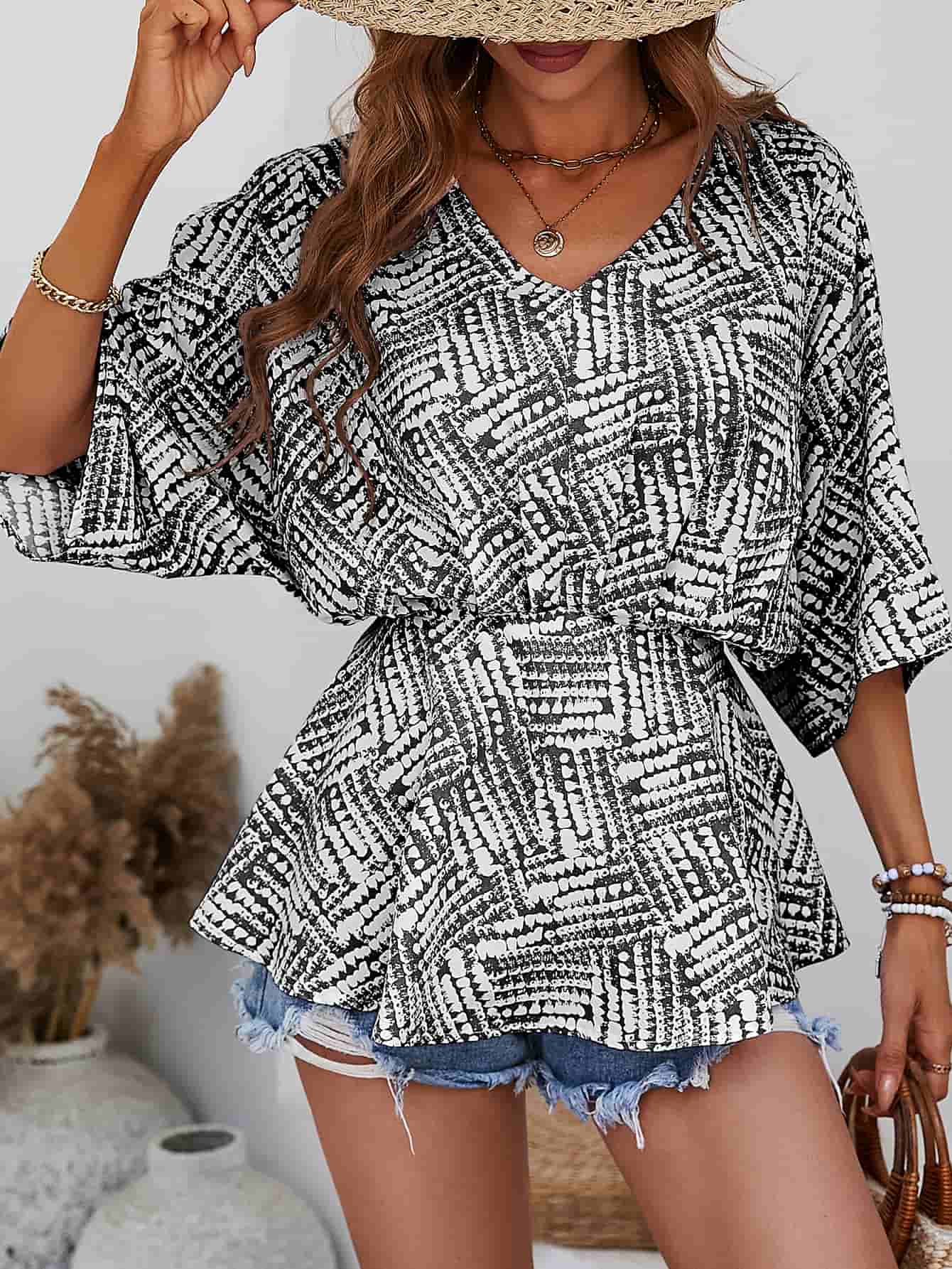 Black abstract print cinched waist blouse with V-neck and dolman sleeves.