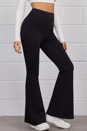 Black flare trousers with a high waist, styled with a white top and sneakers.