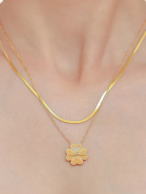 Gold layered necklace with clover charm spelling "maman" and a small diamond detail.