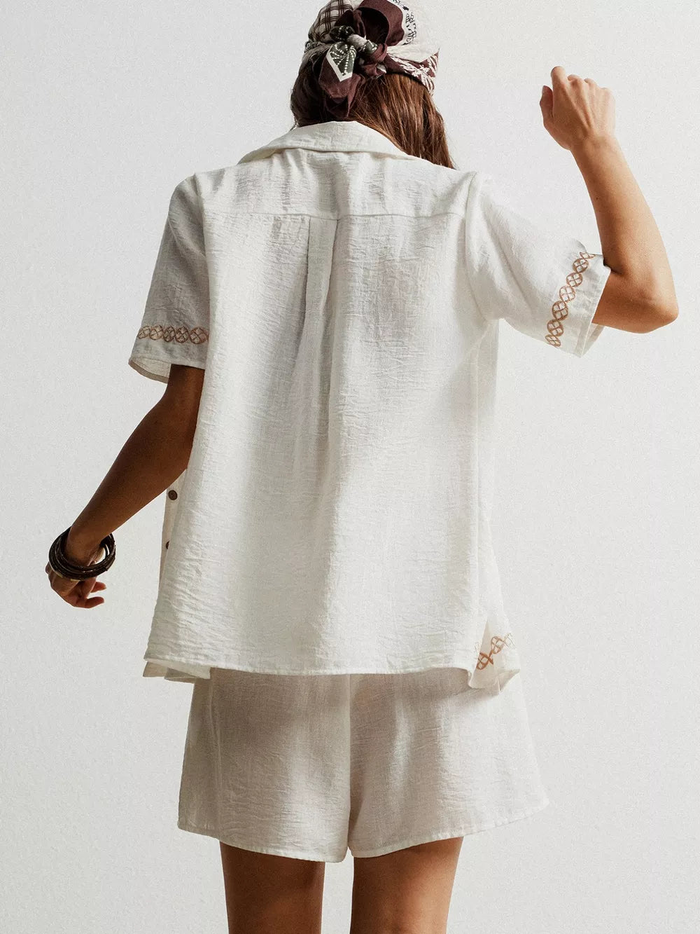 White geometric embroidered button-up shirt and shorts set with textured fabric.