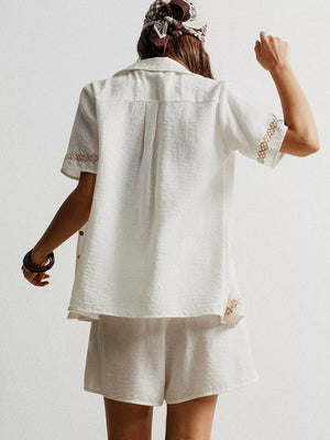 White geometric embroidered button-up shirt and shorts set with textured fabric.