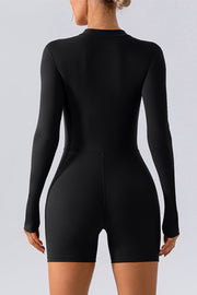 Black performance romper with zip detail, long sleeves, and short legs.