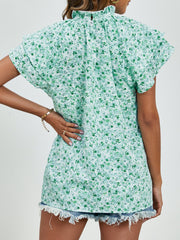 Light green floral blouse with ruffled neckline and flutter sleeves