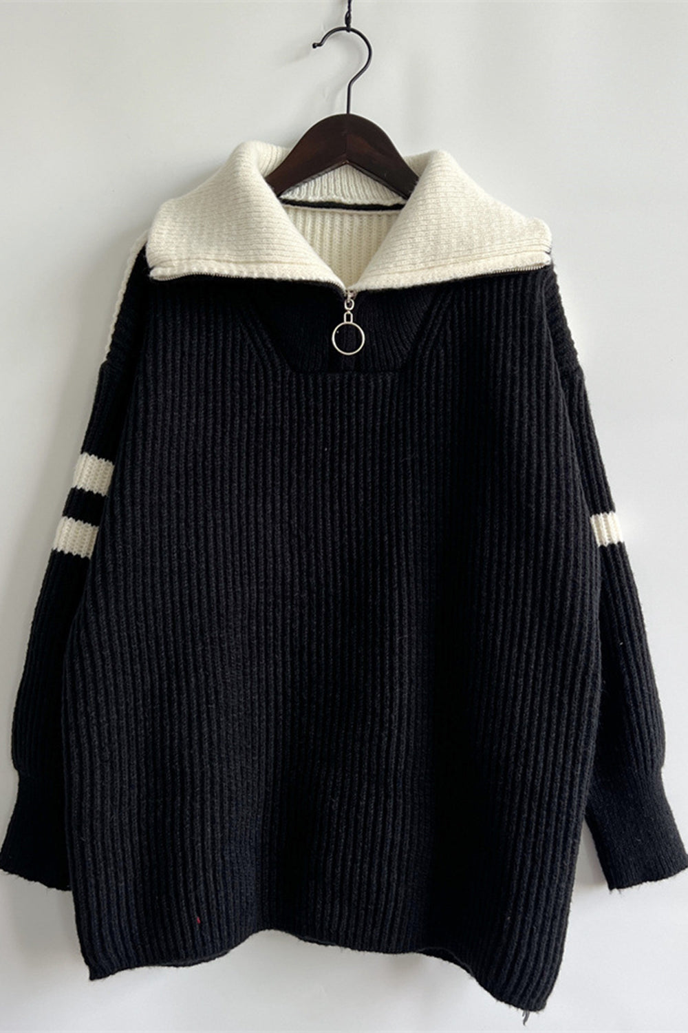 Black ribbed knit quarter-zip sweater with white collar and striped sleeves.
