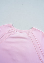 Blush pink sweatshirt with crew neck and ribbed seam details on raglan sleeves.