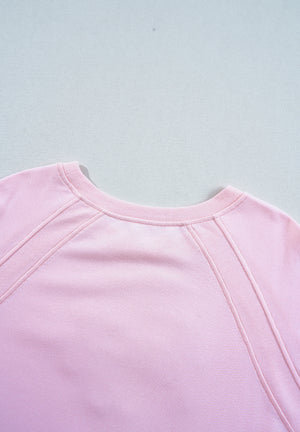 Blush pink sweatshirt with crew neck and ribbed seam details on raglan sleeves.
