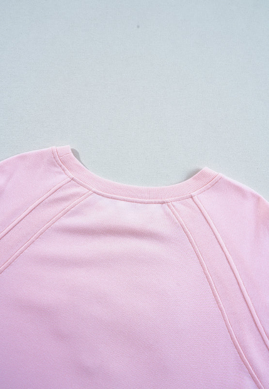 Blush pink sweatshirt with crew neck and ribbed seam details on raglan sleeves.