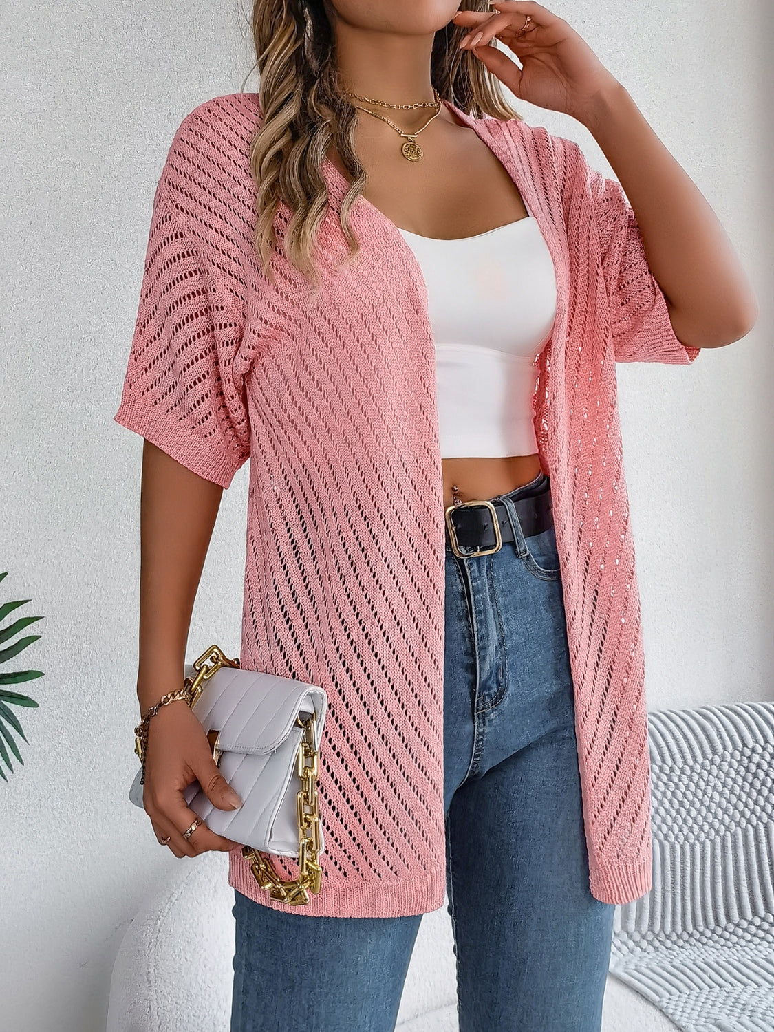 Pink open-knit slouchy cardigan with short sleeves and diagonal stitch detail.