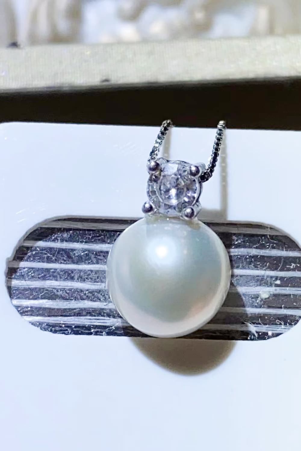 Solitaire pearl pendant necklace in silver with a clear cubic zirconia accent.