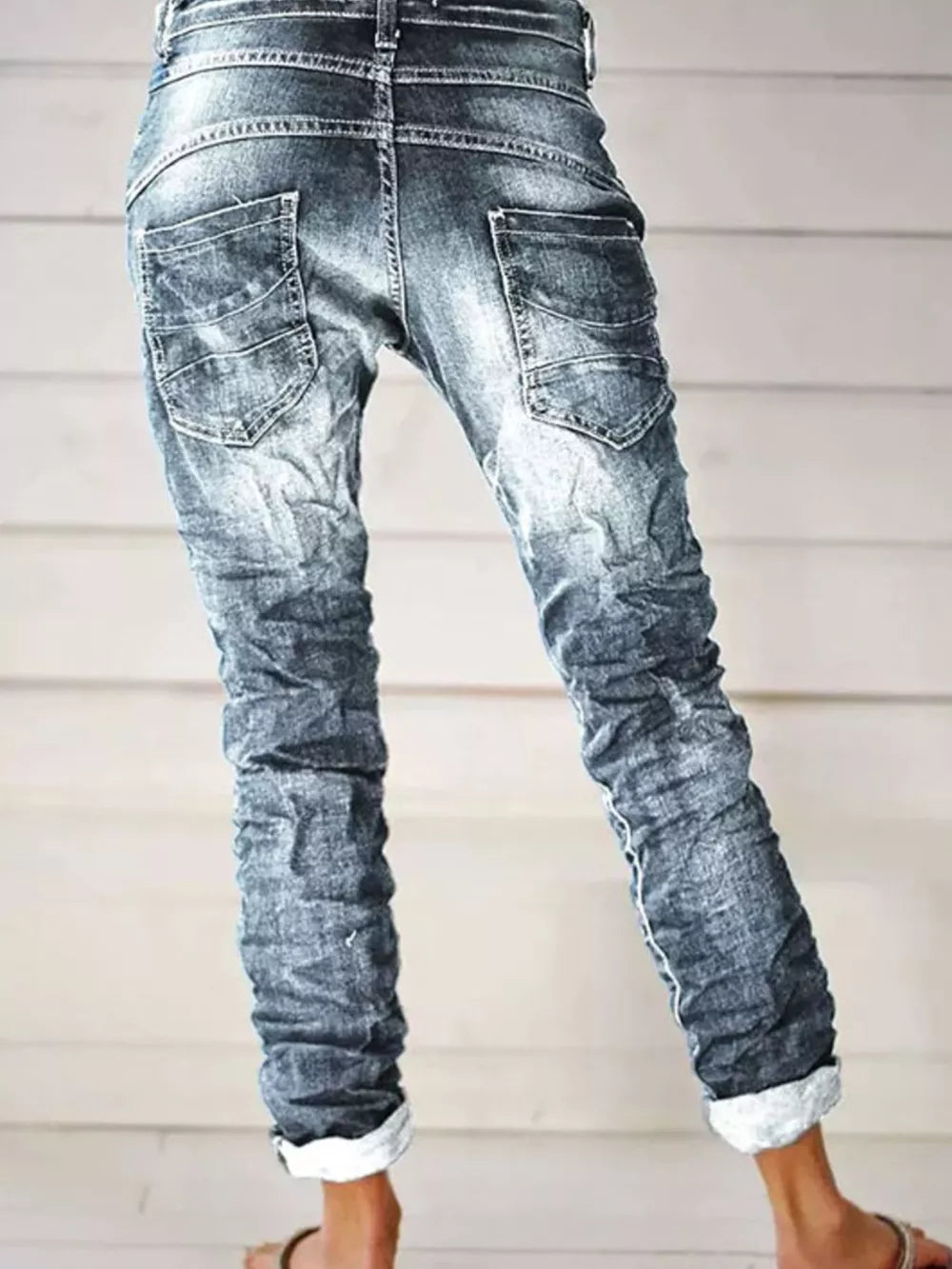 Dark blue cuffed button-fly jeans with distressed detailing and a relaxed fit.