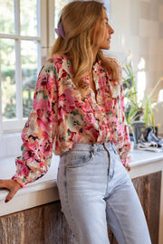 Pink floral print blouse with ruffle yoke and button front, long sleeves.
