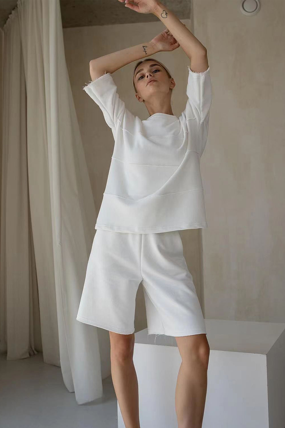 White relaxed fit sweatshirt and shorts set with seam details and raw edges.