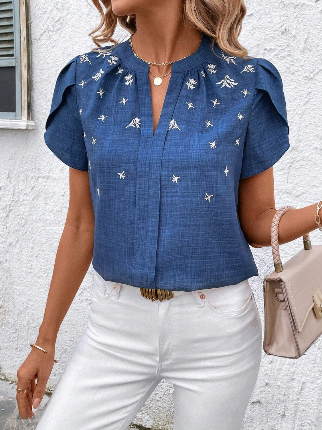 Blue embroidered floral keyhole blouse with short flutter sleeves.