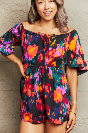 Off-shoulder playsuit with abstract print, tie neck, and ruffled sleeves in multicolor.