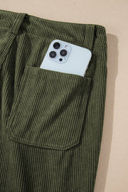 Olive corduroy flared leg trousers with a phone in the pocket.