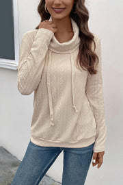Beige textured knit sweater with cowl neck and drawstring detail.