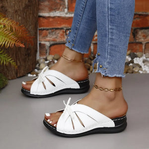 White leather lace-up cutout slides with a black sole and wedge heel.