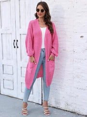 Ribbed knit maxi cardigan in bright pink with pockets and balloon sleeves, worn open over a white top.