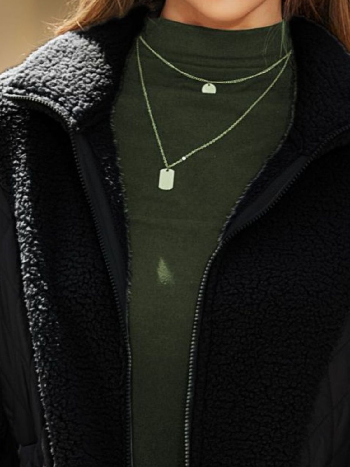 Black quilted sherpa panel zip jacket with a mock neck and layered necklaces.