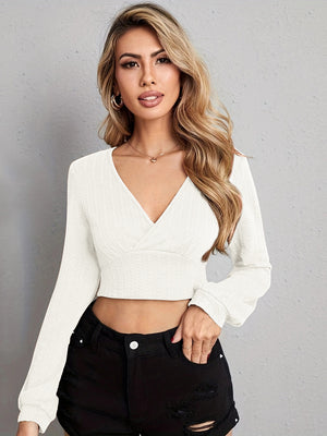 Textured white wrap-front crop top with long sleeves and a V-neck.