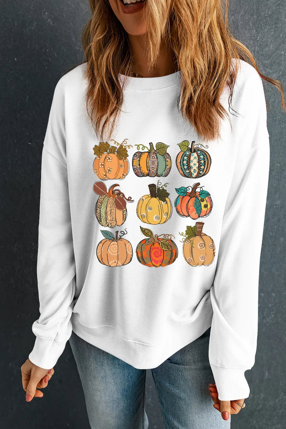 White crewneck sweatshirt with a graphic print of nine decorative pumpkins in a grid pattern.