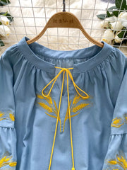 Blue tie-neck blouse with yellow wheat embroidery and bell sleeves.