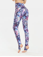 Prism Palm stirrup leggings in dark blue with a colorful floral print and black trim.