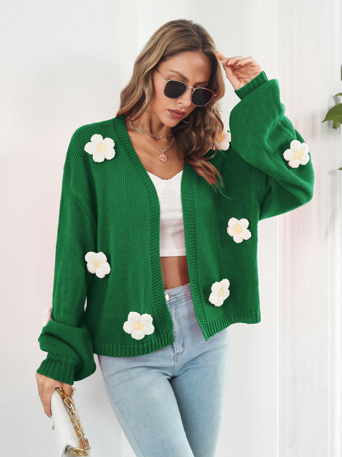Green knit cardigan with floral appliqués and balloon sleeves.