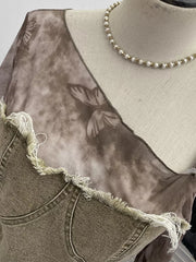 Edgy asymmetrical t-shirt in gray black with butterfly print mesh and distressed denim detail.