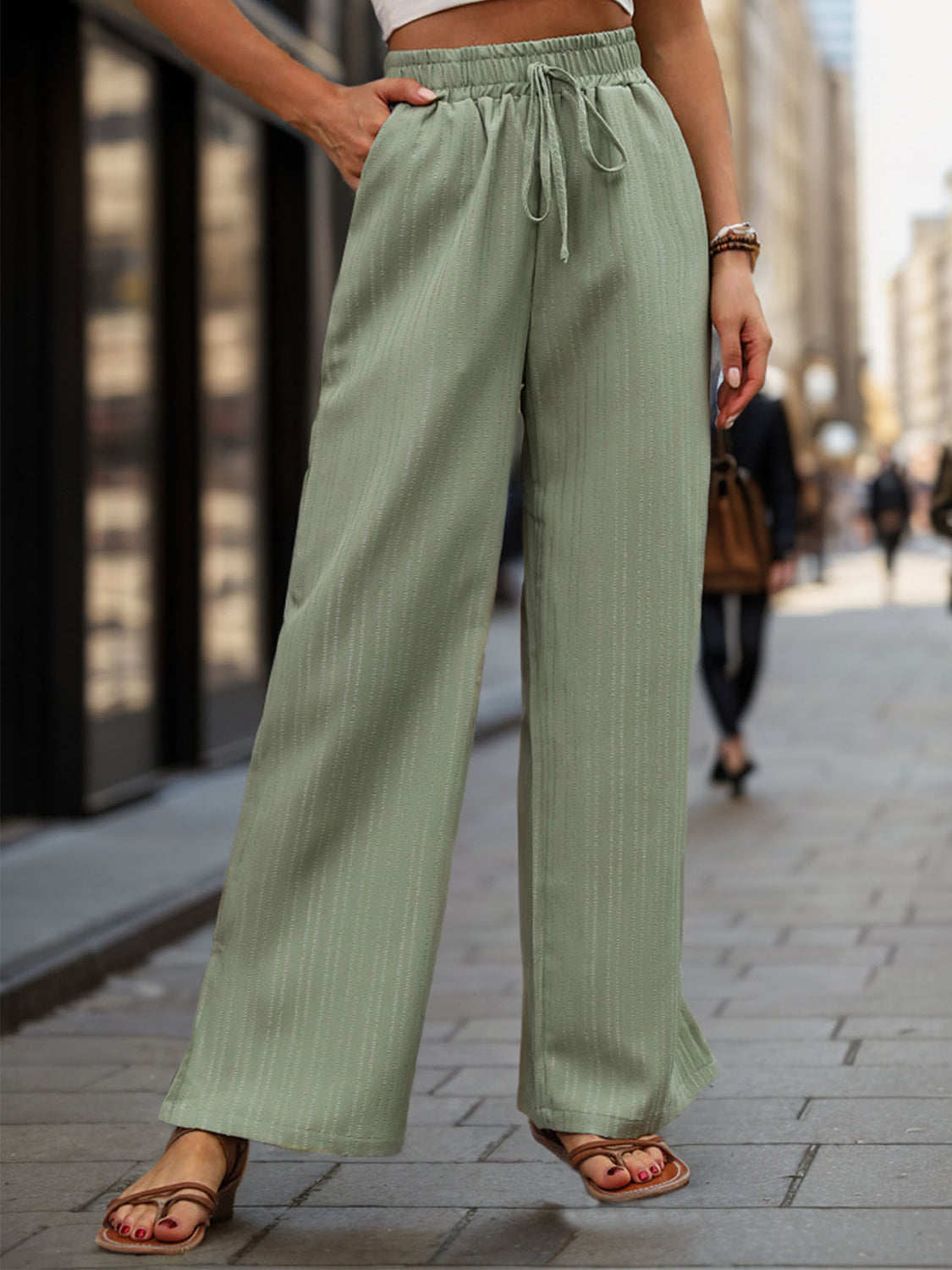 Sage linen blend palazzo trousers with drawstring waist and subtle vertical pinstripe detail.
