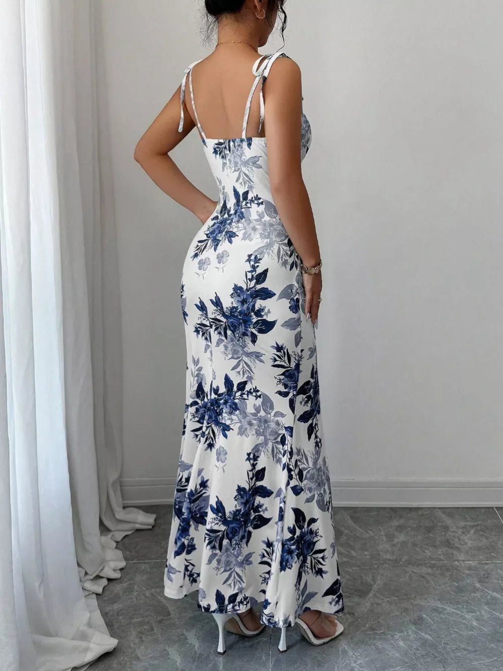 Maxi dress in white with blue floral print, tie straps, and a flared hem.