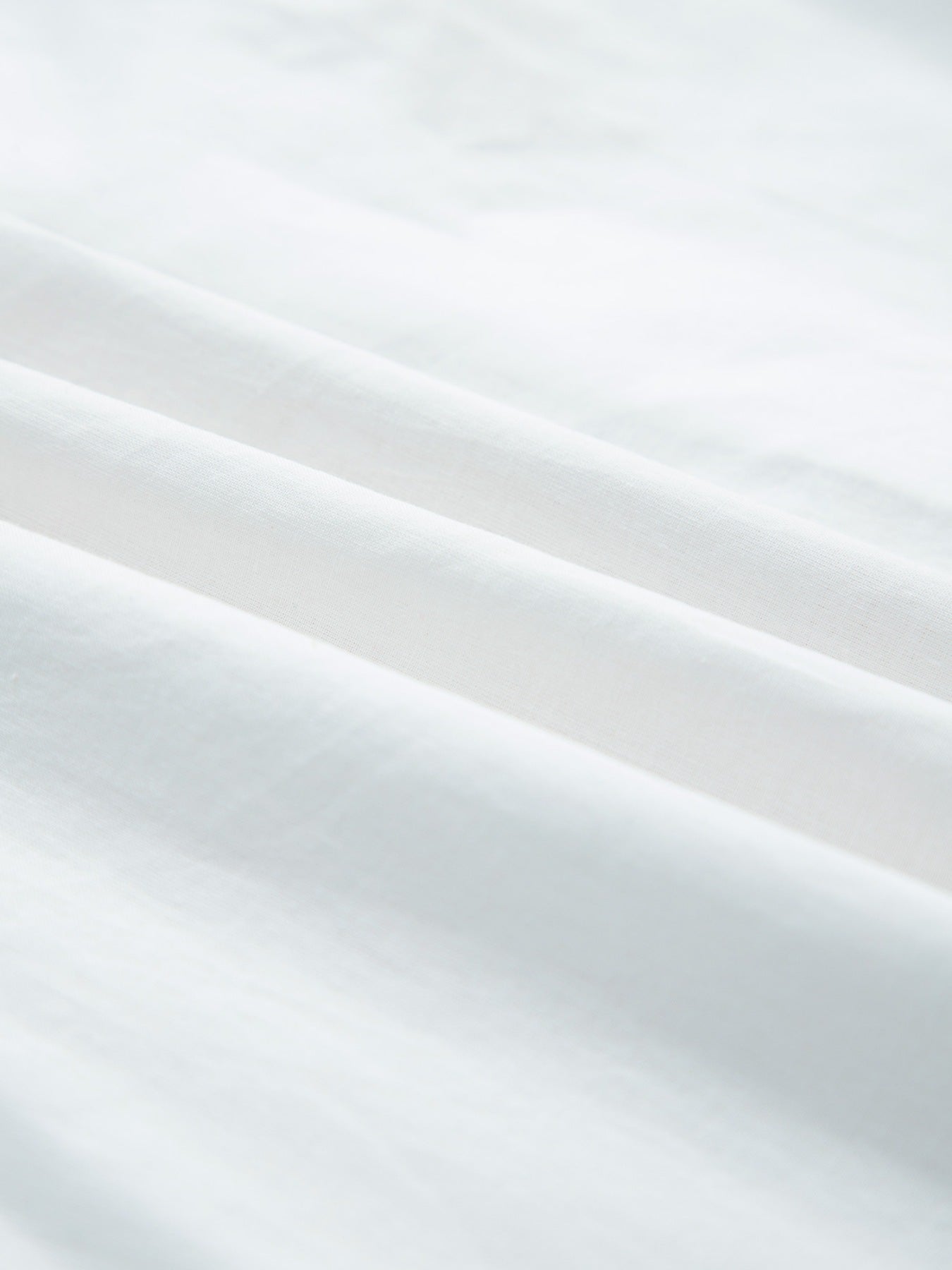 White cotton eyelet embroidered sheer shirt with button-down detail.