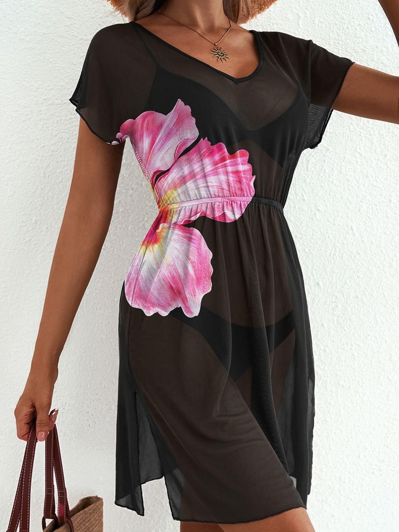 Black sheer mini dress with pink floral print, V-neck, short sleeves, and side slit.