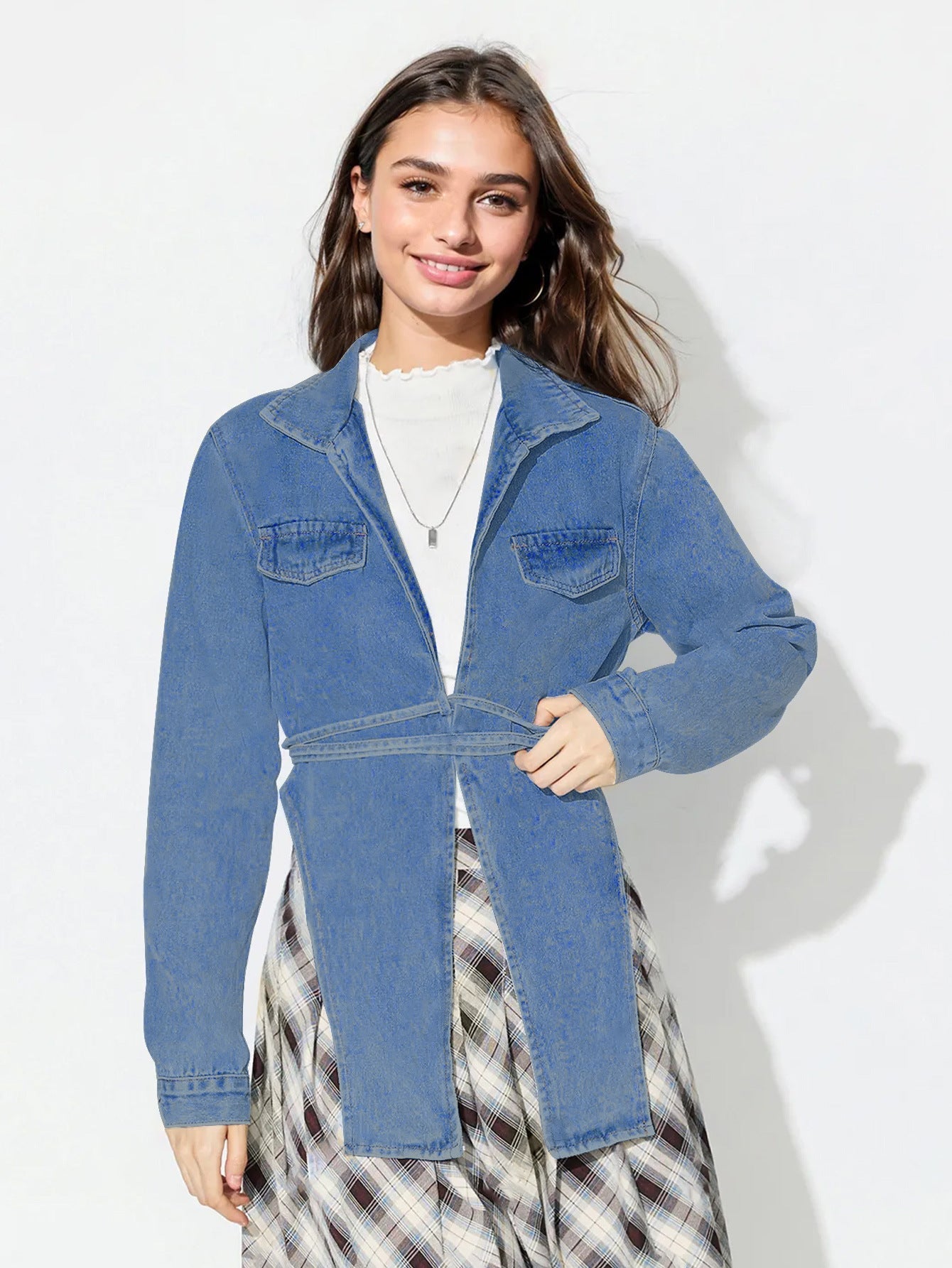 Medium wash denim wrap jacket with tie waist and asymmetric hem.