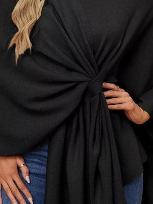 Black knit cape top with a tie-front knot and draped elegance.