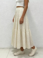 Ruched floral tiered maxi skirt in beige with a ruffled hem, styled with a crop top and sneakers.