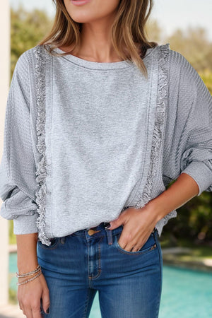 Gray waffle knit sweater with fringe trim detail and crew neck.