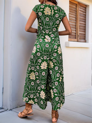Botanical print culotte jumpsuit in dark green with cap sleeves and wide legs.