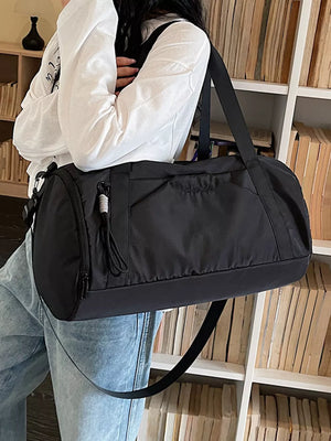 Black nylon travel duffle bag with tassel detail and adjustable strap.