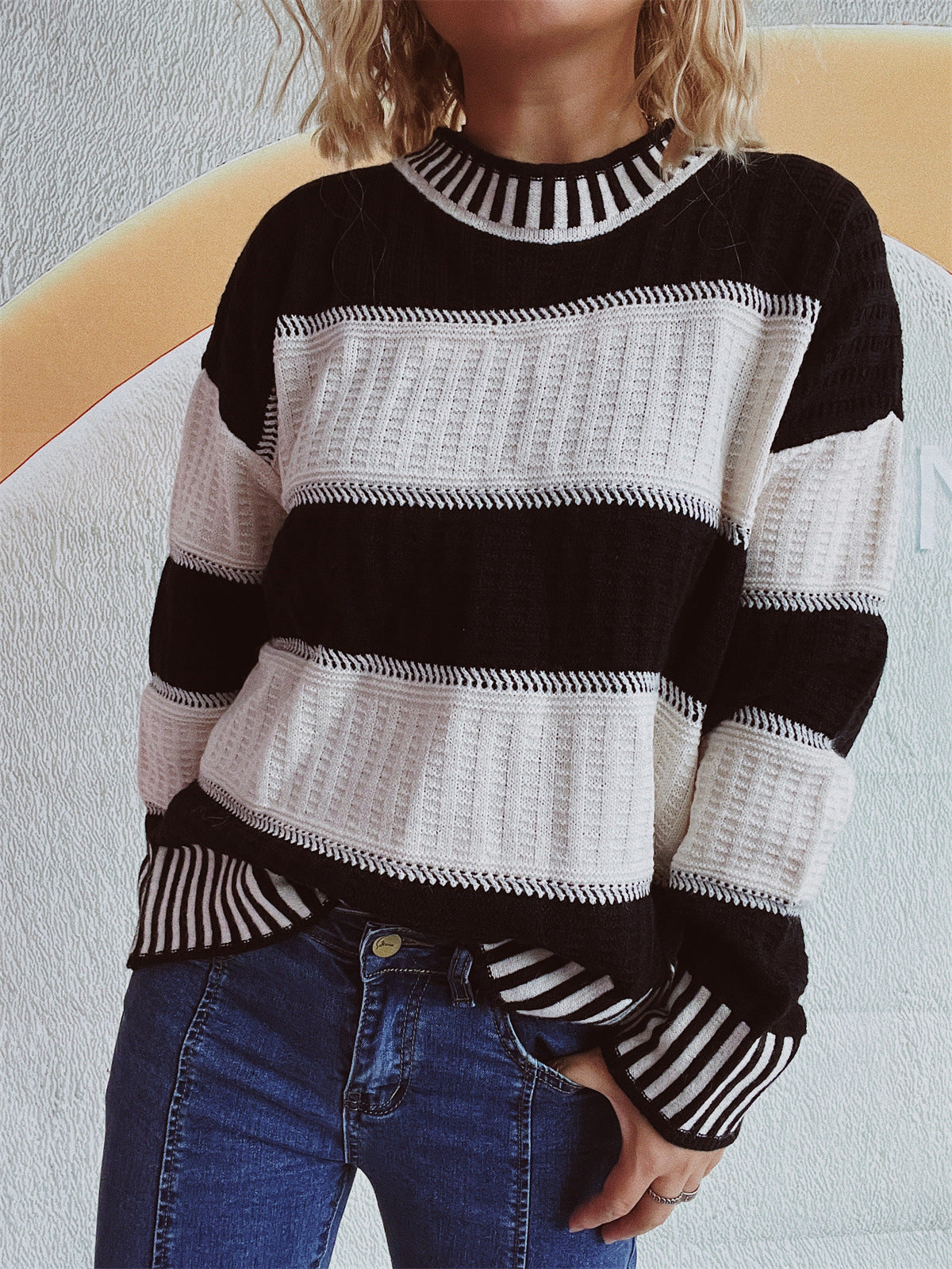 Black and white striped mock neck knit sweater with textured panels.