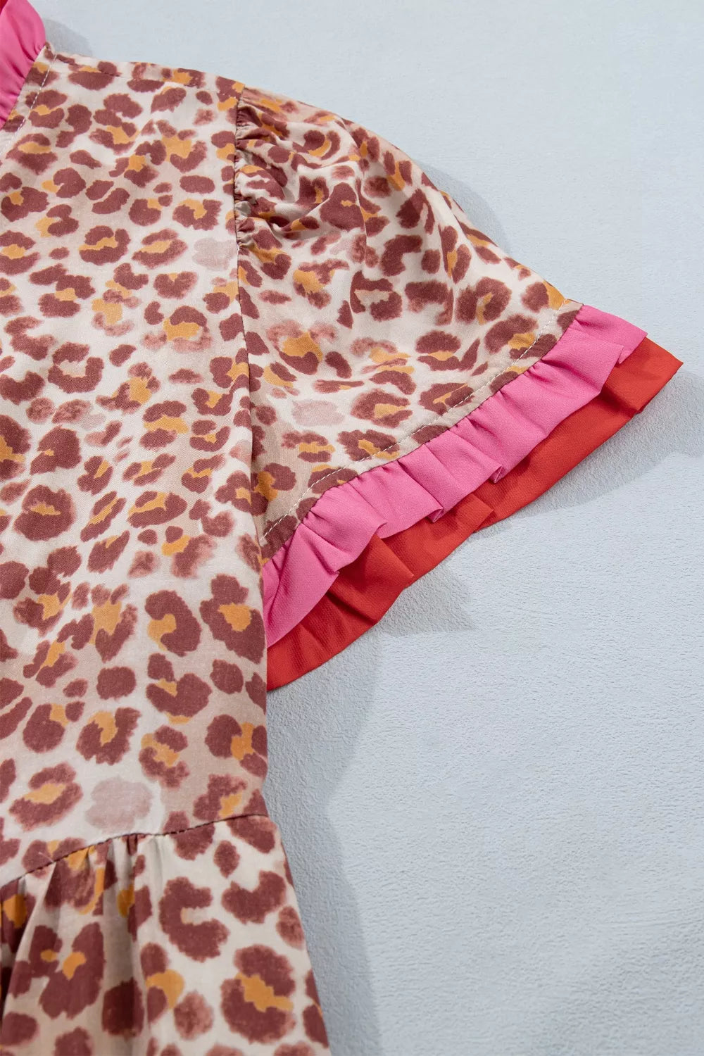 Leopard print dress with ruffled short sleeves in pink and red trim.