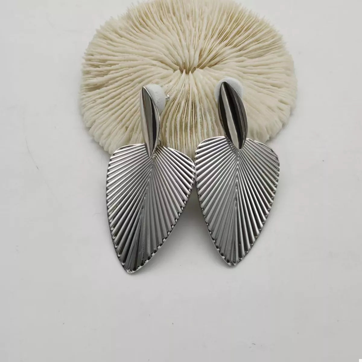 Silver leaf silhouette dangle earrings with textured surface detail.
