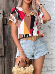 Geometric print V-neck blouse with short sleeves, styled with denim shorts and a straw bag.