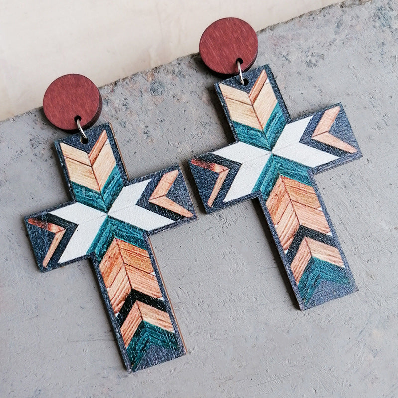 Geometric cross statement earrings with wood stud and tribal pattern in beige, teal, and white.