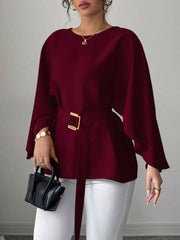 Wine red belted blouse with batwing sleeves and gold buckle detail.