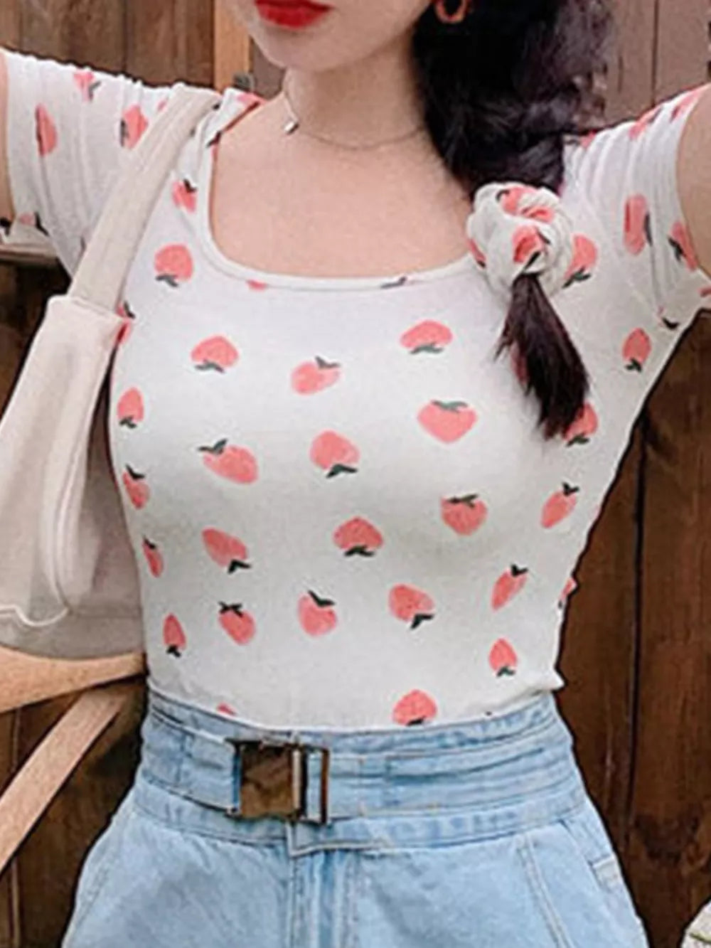 White t-shirt with peach print, square neck, and short sleeves.