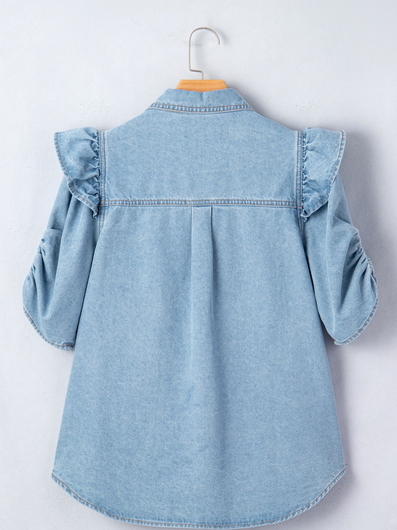 Light wash denim button-down shirt with ruffled shoulders and ruched sleeves.
