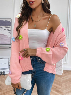 Pink knit cardigan with embroidered multicolor flowers, open front, long sleeves.