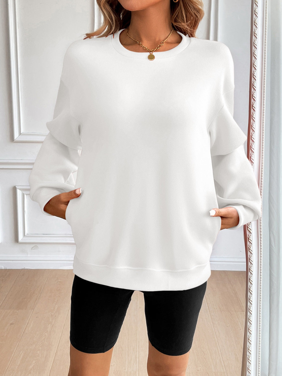 Relaxed fit white sweatshirt with crewneck, long sleeves, and front pockets.
