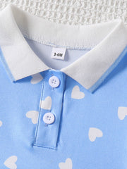 Baby dress with white heart print, blue polo collar, and button placket.